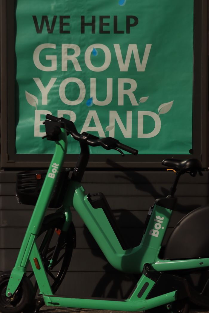 Electric scooter leaning against wall with a brand growth slogan.
